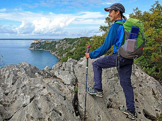Eine Wanderin mit Stöcken an der Küste
