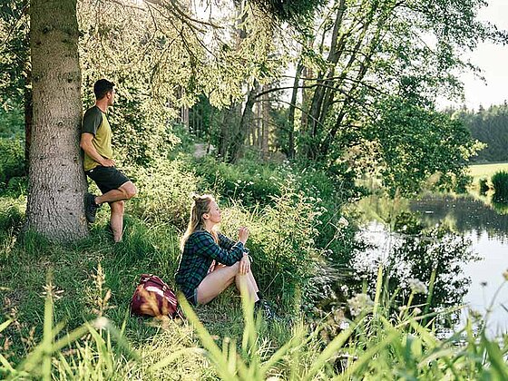 2 Wanderer machen Pause am Ufer eines Baches