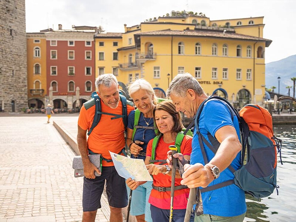 4 Wanderer mit einer Wanderkarte am Stadtplatz von Riva