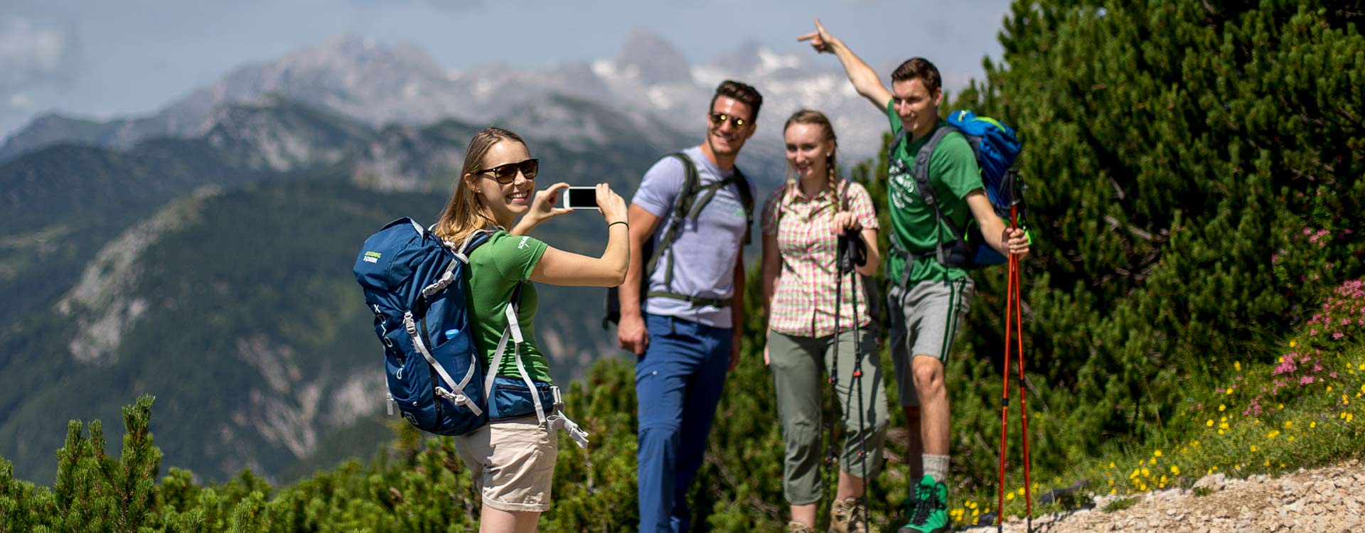4 Wanderer machen ein Foto mit dem Handy, im Hintergrund Berge